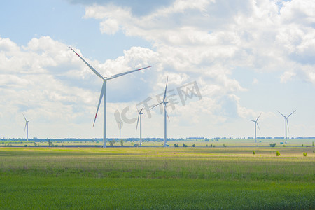 大风车风车摄影照片_阳光明媚的日子里，绿色田野上有许多又大又高的风车。
