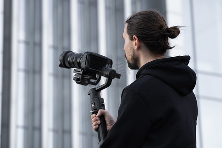 年轻的专业摄影师在 3 轴万向稳定器上持有专业相机。
