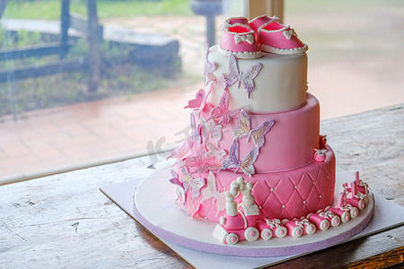 粉色小蝴蝶摄影照片_为小女婴生日庆祝洗礼的拳头蛋糕 — 粉色糖膏分层蛋糕设计无人