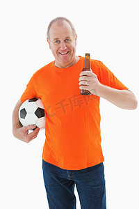 穿着橙色T恤的成熟男人拿着足球和啤酒