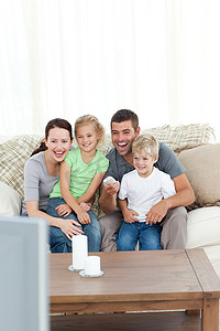 幸福的家庭坐在沙发上看电视时笑着