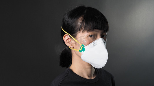 疾病预防背景摄影照片_在冠状病毒检疫情况下，戴着黑色背景面具的亚洲女孩。