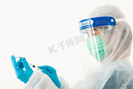 工科学科摄影照片_身穿 PPE 制服的女医学科学家戴着面罩防护罩和塑料面罩，用于疫苗和注射器检疫冠状病毒爆发（COVID-19），在白色背景下隔离