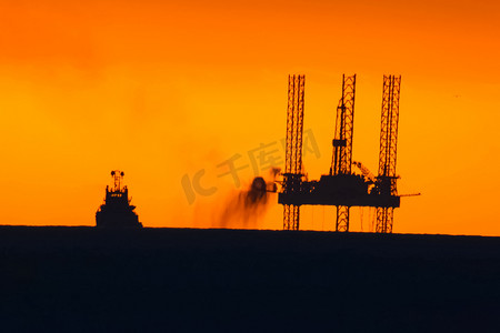 日落时的石油平台与燃烧的火炬。石油平台的拖曳。