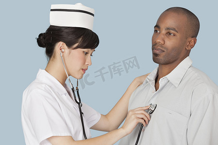 男医生帽子摄影照片_浅蓝色背景下女医生听男病人的心跳