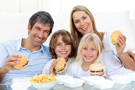 幸福的家庭坐在地板上吃汉堡