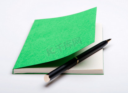 绿色笔记本和圆珠笔