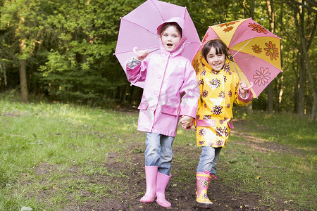 撑着雨伞摄影照片_两姐妹在户外撑着雨伞微笑