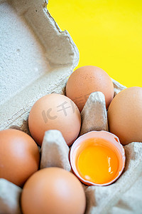 特写破裂的棕色鸡蛋排列在纸盒中从超市购买放置在黄色背景上