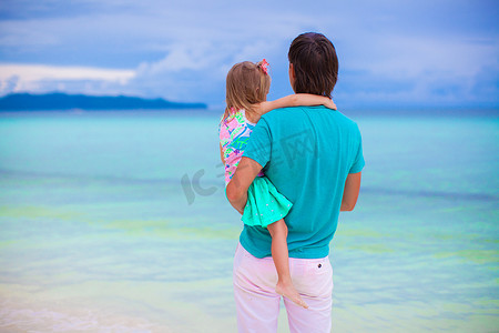 父亲和他的小女儿在热带海滩看海