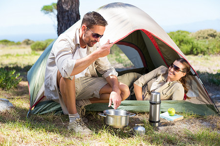 户外情侣在帐篷外的野营炉上做饭