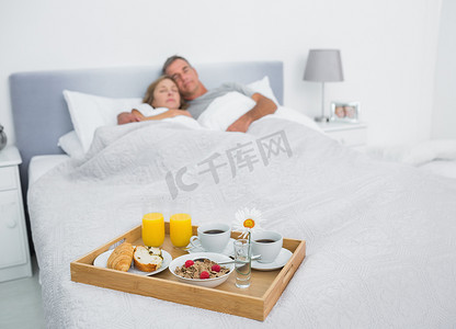 恩爱夫妻睡在床上，早餐托盘
