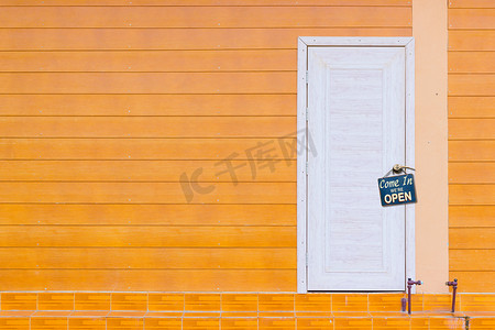 白色木门摄影照片_白色木门和橙色墙壁，上面有旧生锈的金属板