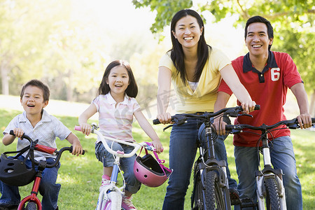 家庭享受摄影照片_家庭在户外骑自行车微笑