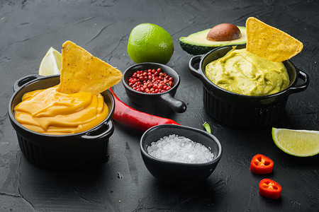 黑色背景中传统墨西哥炸玉米饼的绿色鳄梨酱和黄色奶酪酱