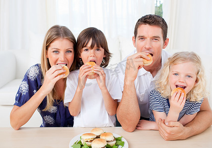 饥饿的家庭在客厅吃汉堡