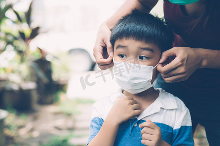 母亲在户外用面罩照顾儿子，以预防流感或 covid-19 疾病，妈妈戴上带有儿童安全的医用面罩，以保护公共流行病的爆发，医学概念。