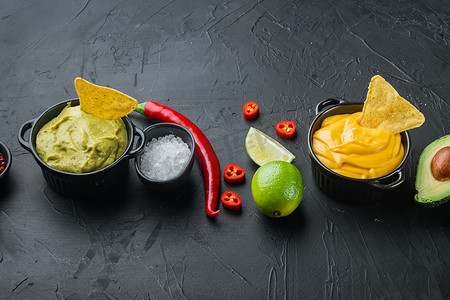 传统墨西哥炸玉米饼的绿色鳄梨酱和黄色奶酪蘸酱，黑色背景，带有文本复制空间
