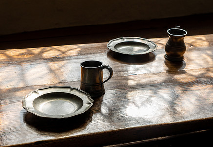 铁制背景摄影照片_大木餐桌上的复古风格锡制杯子和盘子