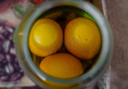 三个鸡蛋放在一个装满黄色油漆的罐子里，等待变成色彩缤纷的复活节彩蛋。