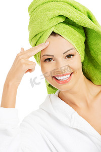 穿着浴袍和头巾的美丽女人正在抚摸她的额头。
