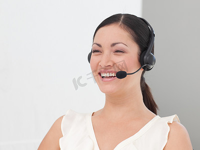 联系热线摄影照片_戴着耳机微笑的美丽国际女商人