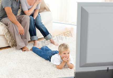 细心的小男孩躺在地板上看电视