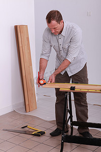 杂工用卷尺测量木板