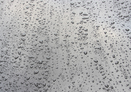 暴雨摄影照片_雨后黑色汽车引擎盖上的水滴