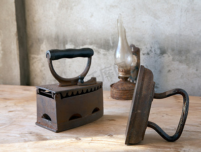 古代的油灯摄影照片_桌上的旧熨斗和油灯