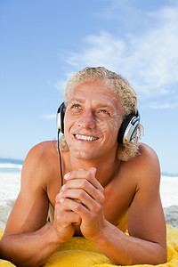 微笑的男人一边用耳机听音乐一边抬起头