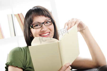 拿着照片摄影照片_年轻女子拿着书、书架放在 bac 上的明亮照片