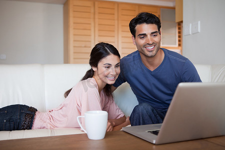 年轻夫妇在喝茶时使用笔记本电脑