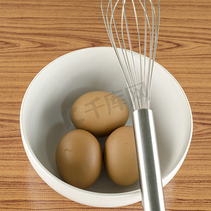 厨具打蛋器插画摄影照片_打蛋器和鸡蛋放入白碗中