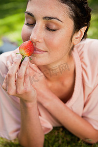 女人躺在草地上闻到草莓味
