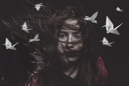 风折纸摄影照片_头发在风中的少女和鸟头纸，折纸