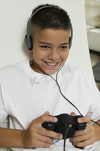 快乐的小男孩戴着耳机玩电子游戏