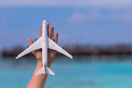 小飞机旅游摄影照片_在绿松石海背景的小白色玩具飞机