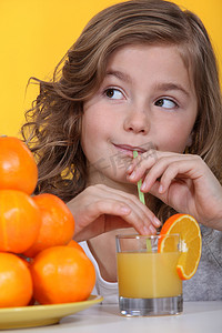 小女孩用橙子和一杯果汁