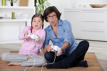 正在玩电脑的人摄影照片_一位母亲和她的女儿正在玩电子游戏。