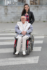 奶奶种地摄影照片_女孩推着轮椅上的高级妇女