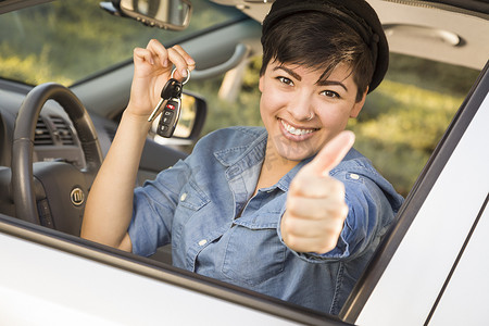 手拿车钥匙摄影照片_快乐的混血女人在车里拿着钥匙