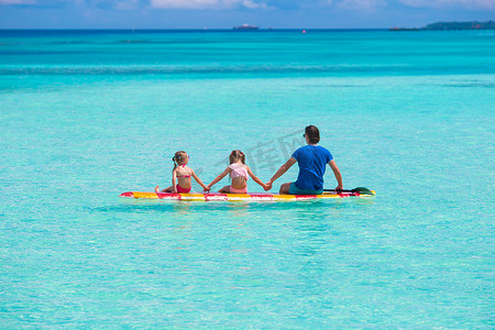 孩子游泳摄影照片_暑假期间，父亲和孩子们在冲浪板上
