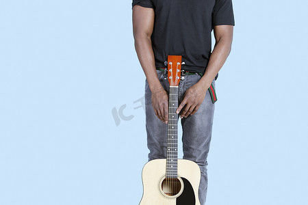 浅蓝色背景中带吉他的非洲裔美国人的中段