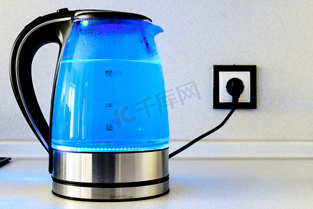 厨房里有灯光的透明茶壶烧水