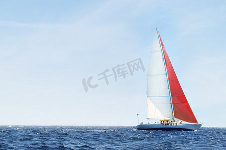 帆船大海摄影照片_宁静的蓝色海洋中天空映衬下的一艘帆船的侧视图