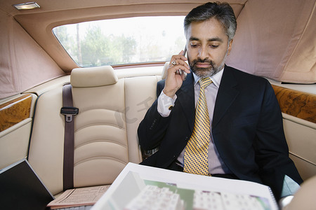 印度商人在车里用手机交流时看着记事本