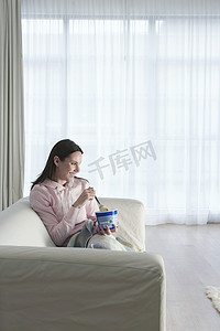 在家沙发上看电视和吃冰淇淋的女人