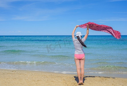 在风大的海滩上拿着布料的年轻女子