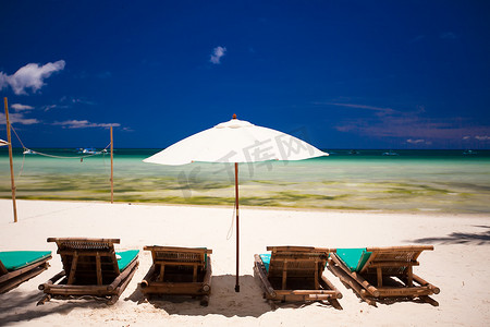 面向泻湖的白色沙滩上的躺椅和遮阳伞